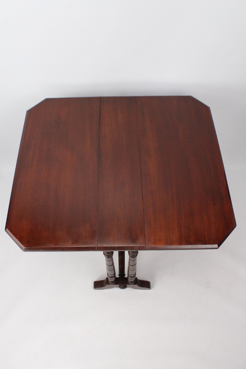 A small Victorian mahogany Sutherland table shown folded with two drop leaves, slender turned spindle legs, and a low stretcher base. View V