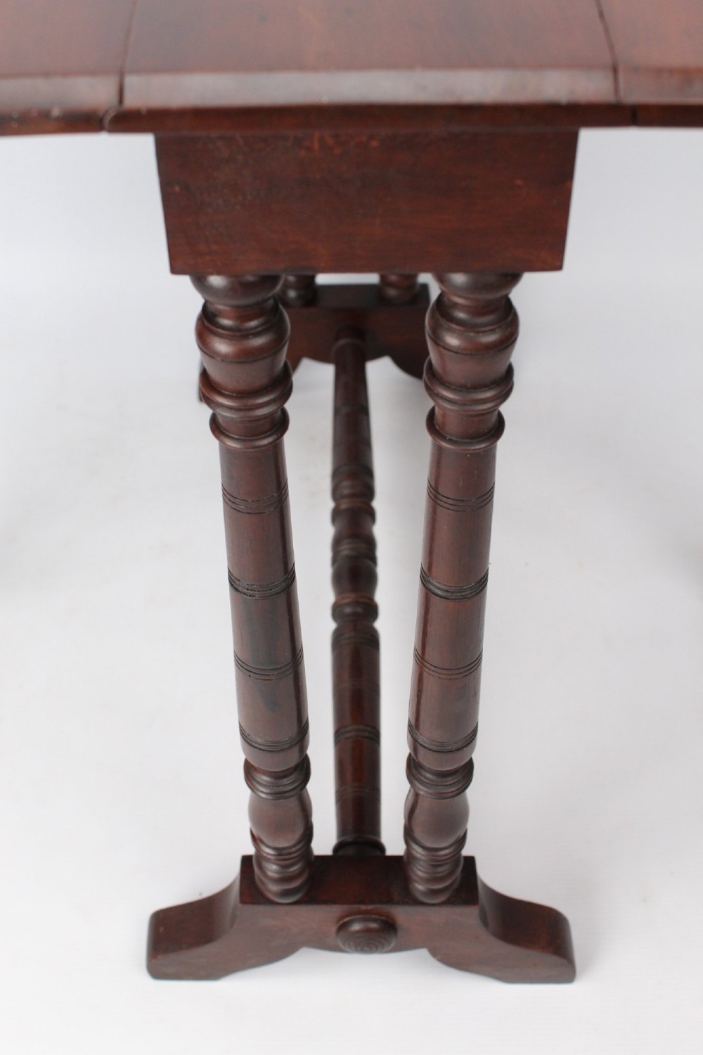 A small Victorian mahogany Sutherland table shown folded with two drop leaves, slender turned spindle legs, and a low stretcher base. View VI