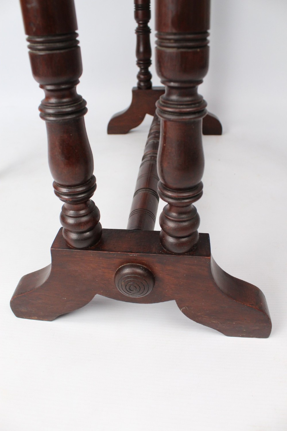 A small Victorian mahogany Sutherland table shown folded with two drop leaves, slender turned spindle legs, and a low stretcher base. View VII