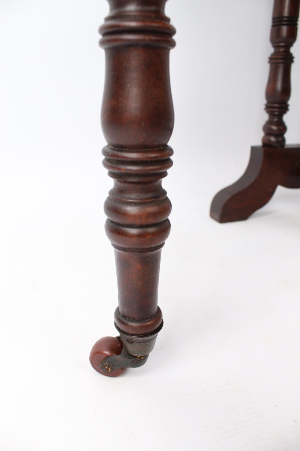 A small Victorian mahogany Sutherland table shown folded with two drop leaves, slender turned spindle legs, and a low stretcher base. View VIII