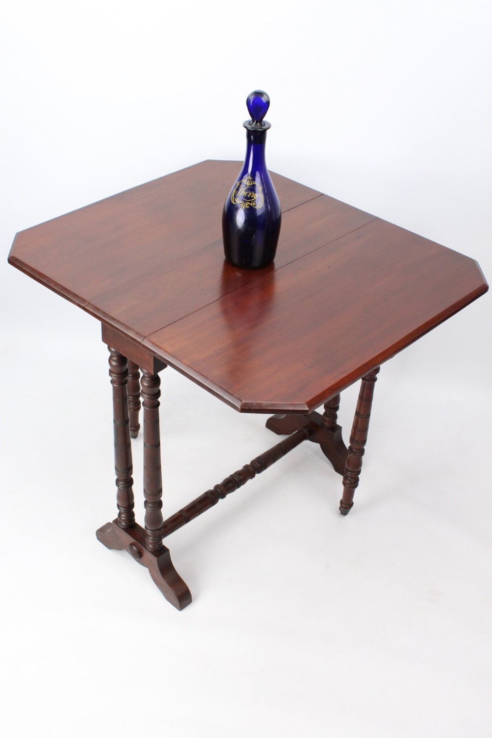 A small Victorian mahogany Sutherland table shown folded with two drop leaves, slender turned spindle legs, and a low stretcher base. View X