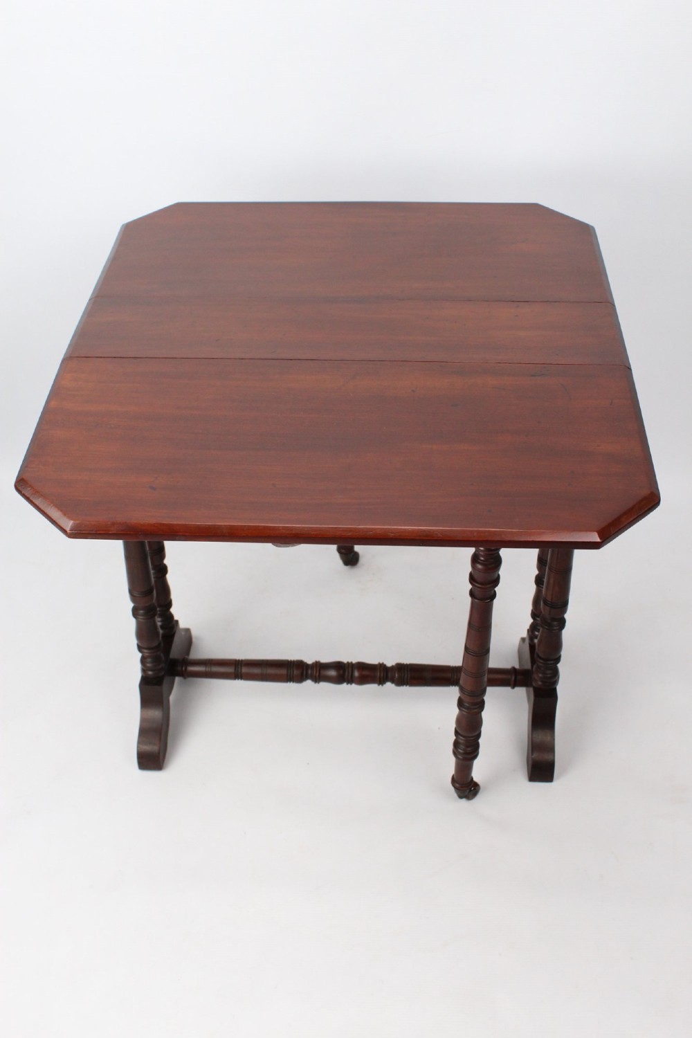 A small Victorian mahogany Sutherland table shown folded with two drop leaves, slender turned spindle legs, and a low stretcher base. View XI