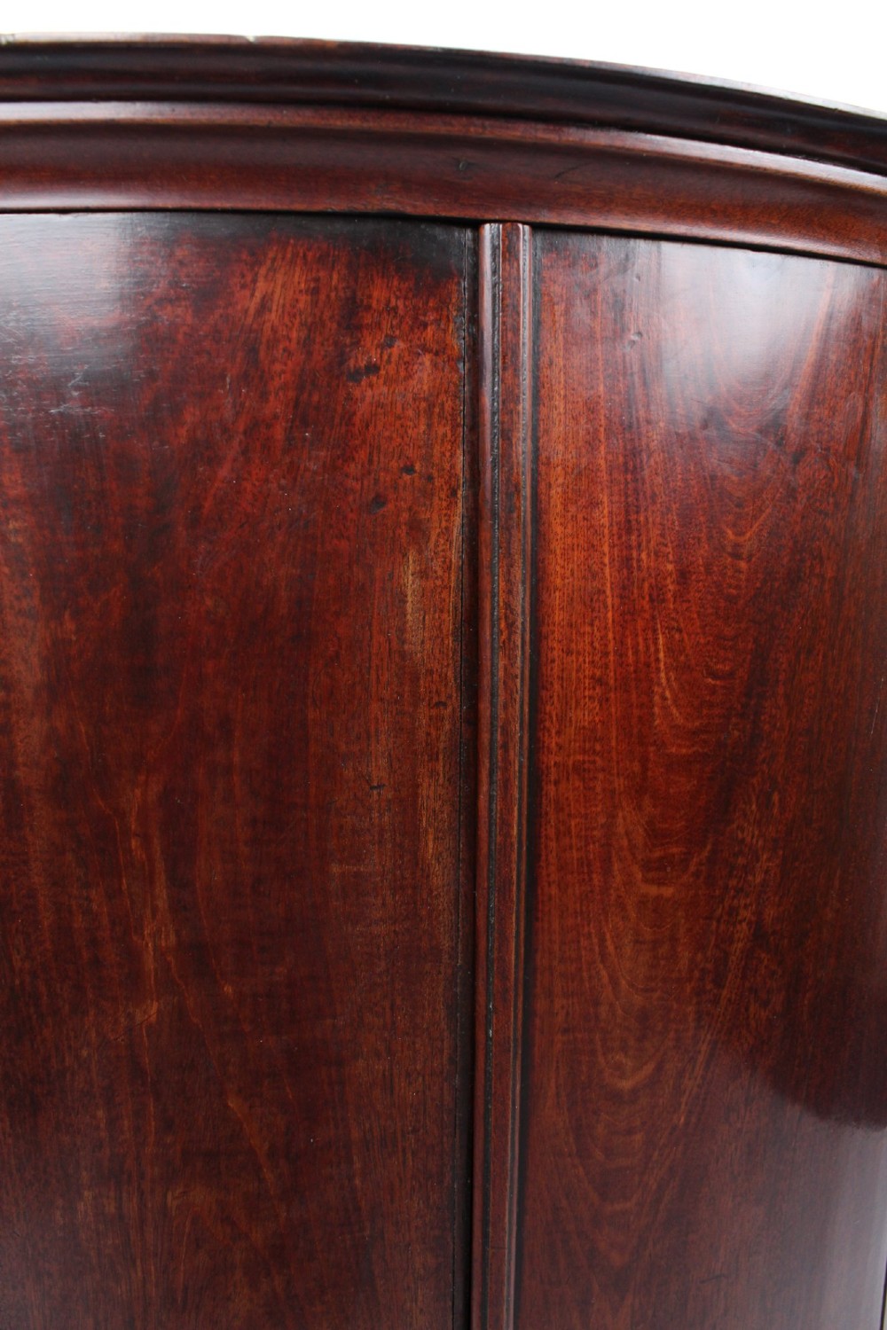 A Georgian mahogany bow front corner cupboard with twin curved doors and decorative brass hinges and keyhole escutcheons. View IX