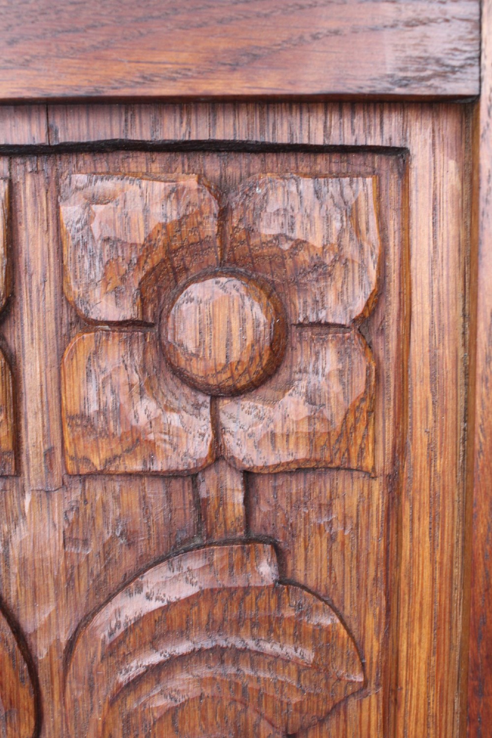 A small Edwardian Arts and Crafts oak wall cabinet featuring a single door decorated with a carved stylized floral panel and small brass hinges. View VII