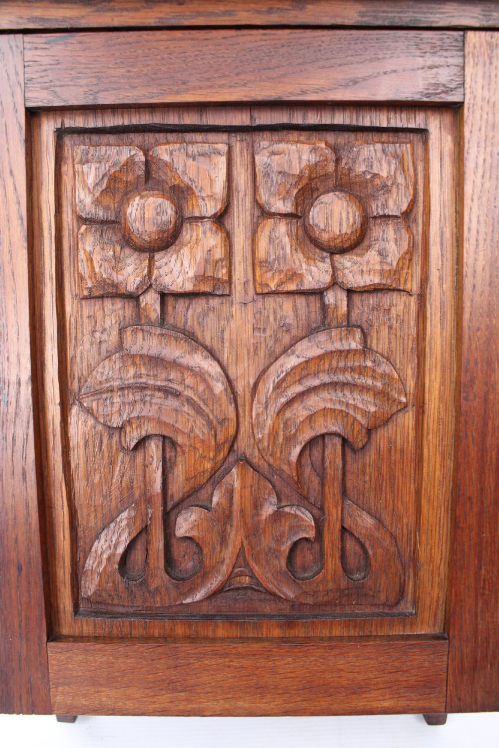 A small Edwardian Arts and Crafts oak wall cabinet featuring a single door decorated with a carved stylized floral panel and small brass hinges. View VIII