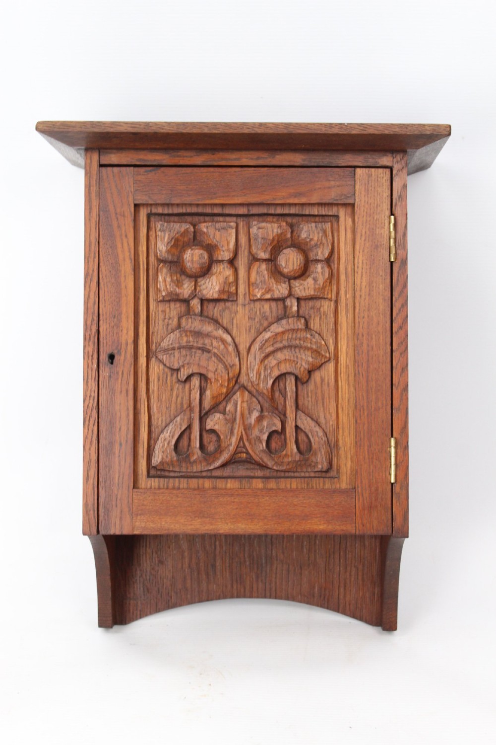 A small Edwardian Arts and Crafts oak wall cabinet featuring a single door decorated with a carved stylized floral panel and small brass hinges. View XI