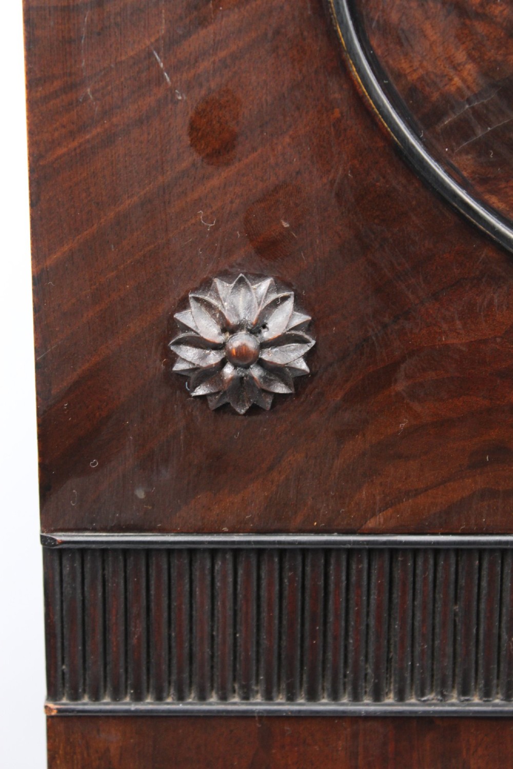 An Edwardian dark mahogany pedestal cabinet featuring an oval flame mahogany panel, carved scroll frieze, and square tapered legs. View XI