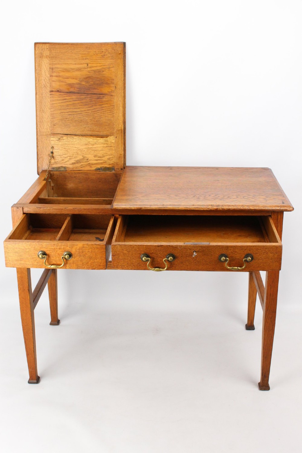 A late Victorian Arts and Crafts oak writing desk featuring drawers with brass swan-neck handles and tapered square legs. View V