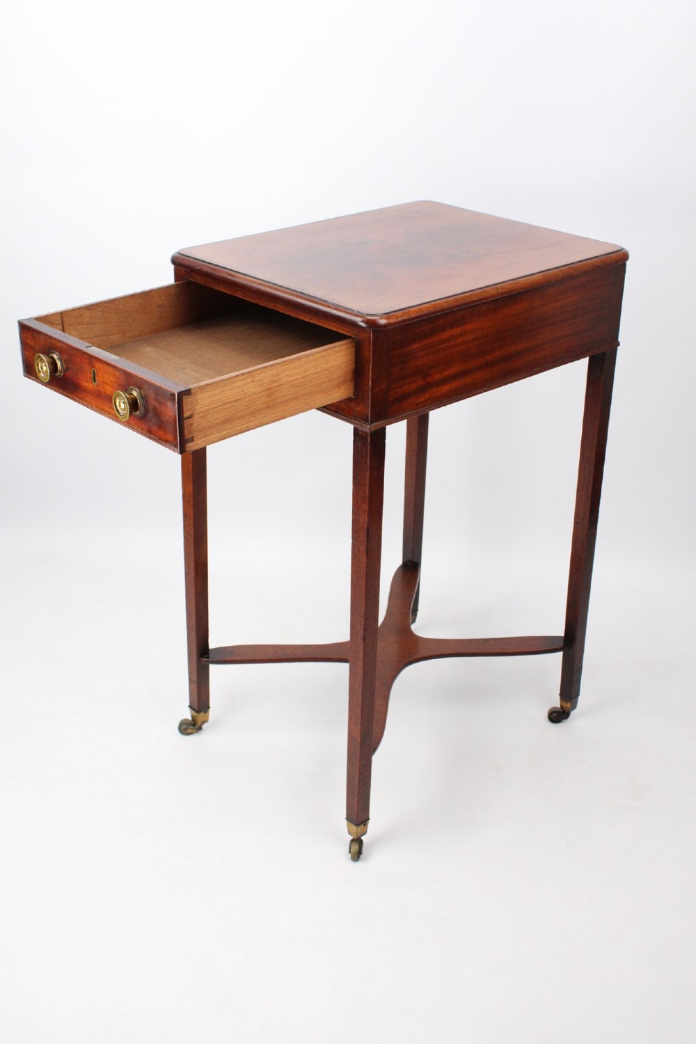 A small Georgian mahogany side table featuring a single drawer with brass ring handles, square tapered legs joined by an X-form stretcher, and brass castors. View III
