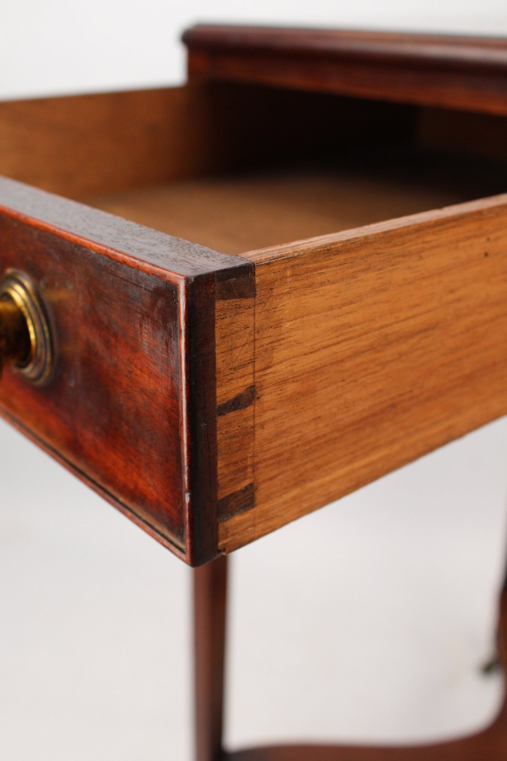 A small Georgian mahogany side table featuring a single drawer with brass ring handles, square tapered legs joined by an X-form stretcher, and brass castors. View VI