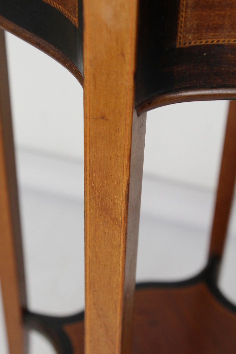 A tall Edwardian mahogany plant stand featuring shaped inlaid panels, four slender splayed legs, a lower shelf, and a dark metal liner. View IX