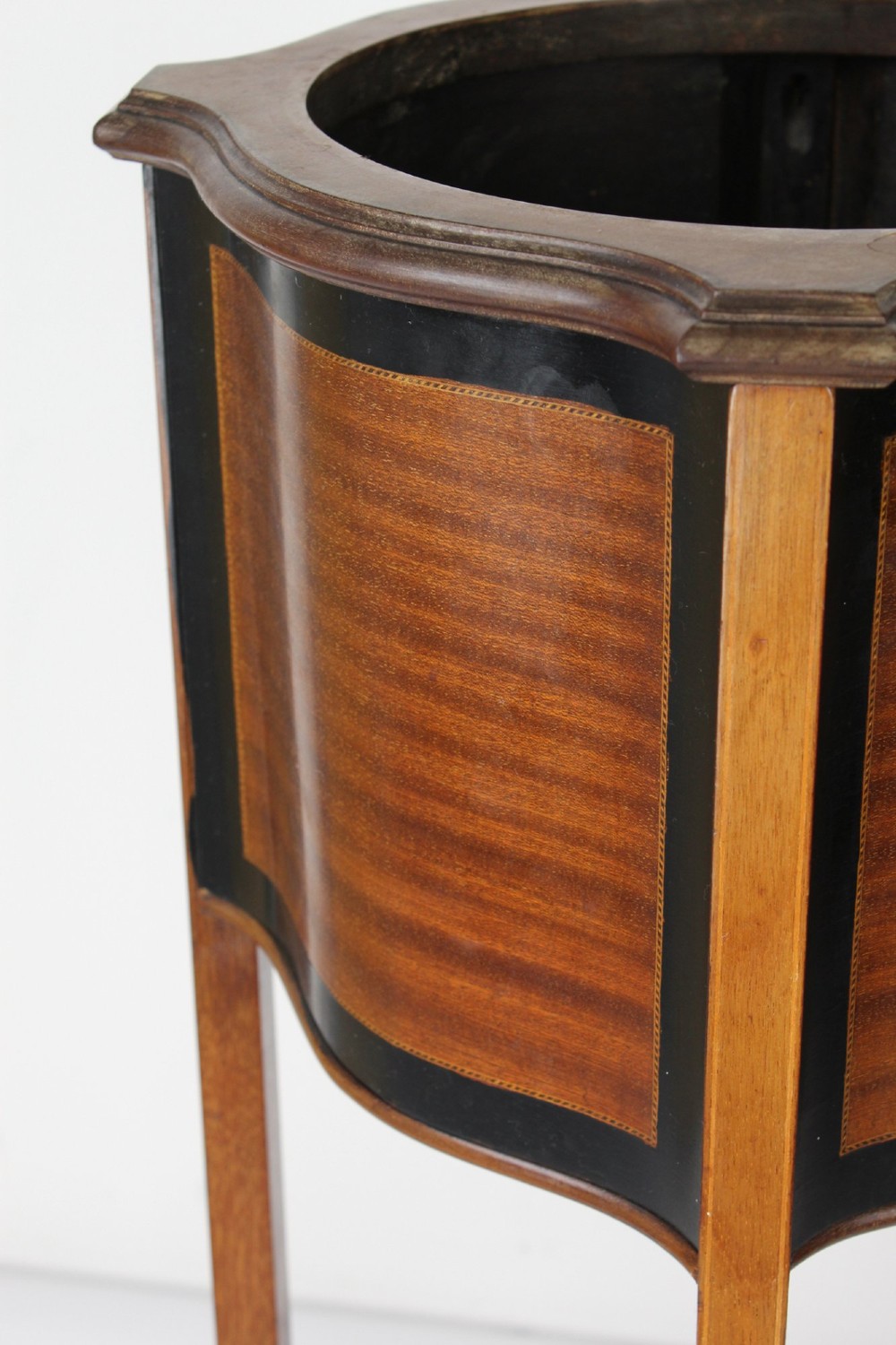 A tall Edwardian mahogany plant stand featuring shaped inlaid panels, four slender splayed legs, a lower shelf, and a dark metal liner. View XI