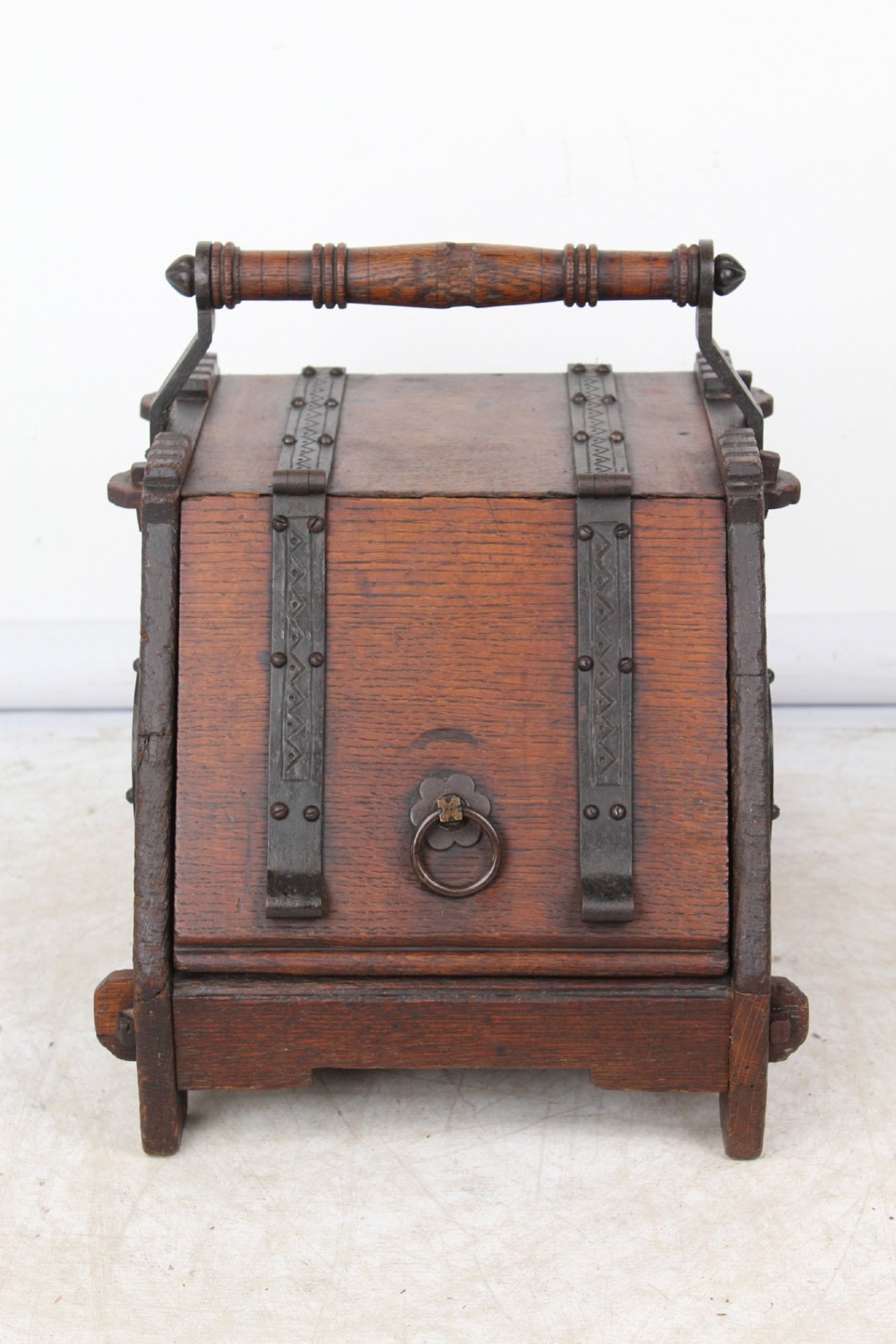 A Victorian Gothic Revival dark oak coal scuttle featuring sloped timber lids, a turned handle, and black wrought iron scrollwork straps. View II