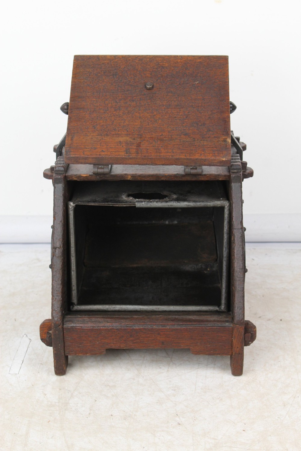 A Victorian Gothic Revival dark oak coal scuttle featuring sloped timber lids, a turned handle, and black wrought iron scrollwork straps. View III