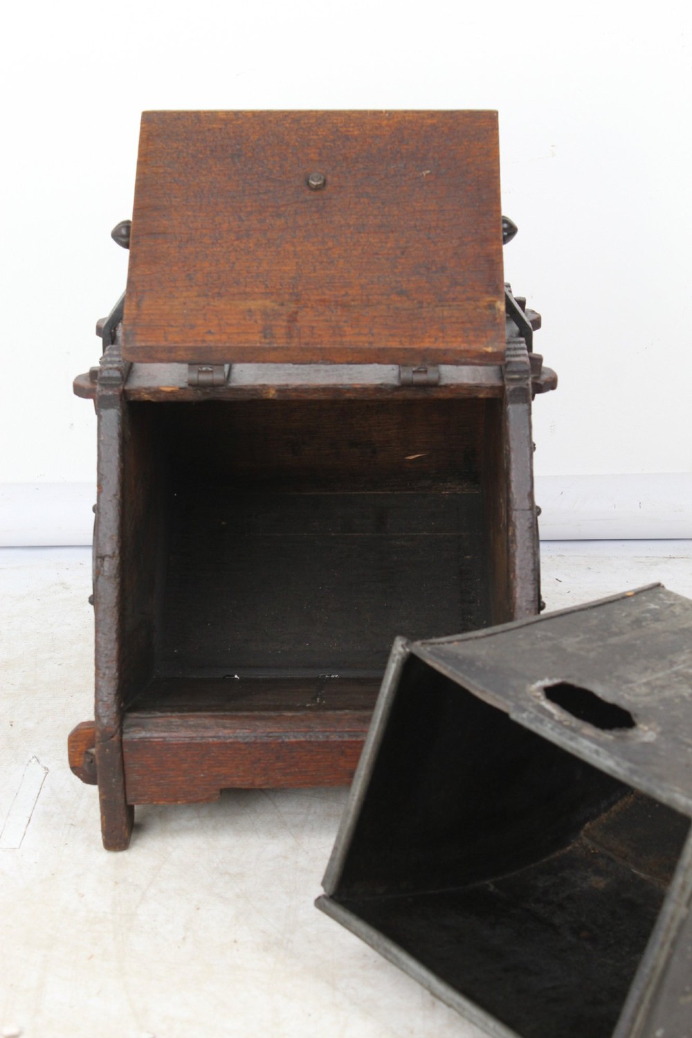 A Victorian Gothic Revival dark oak coal scuttle featuring sloped timber lids, a turned handle, and black wrought iron scrollwork straps. View IV