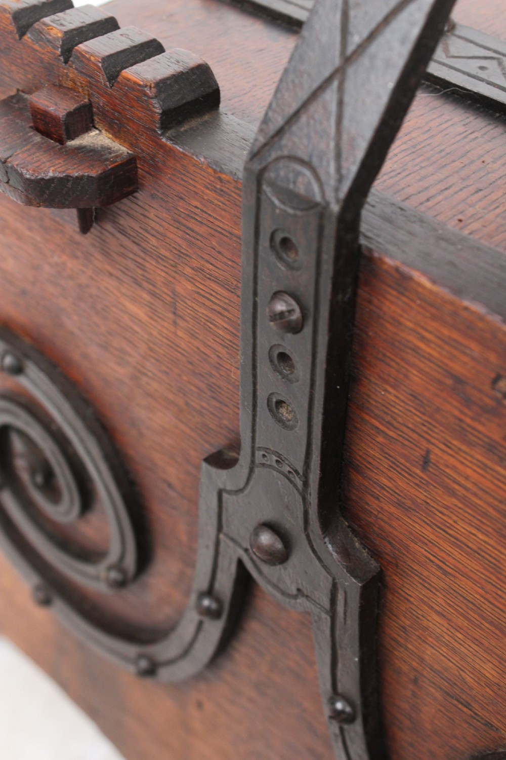 A Victorian Gothic Revival dark oak coal scuttle featuring sloped timber lids, a turned handle, and black wrought iron scrollwork straps. View VIII