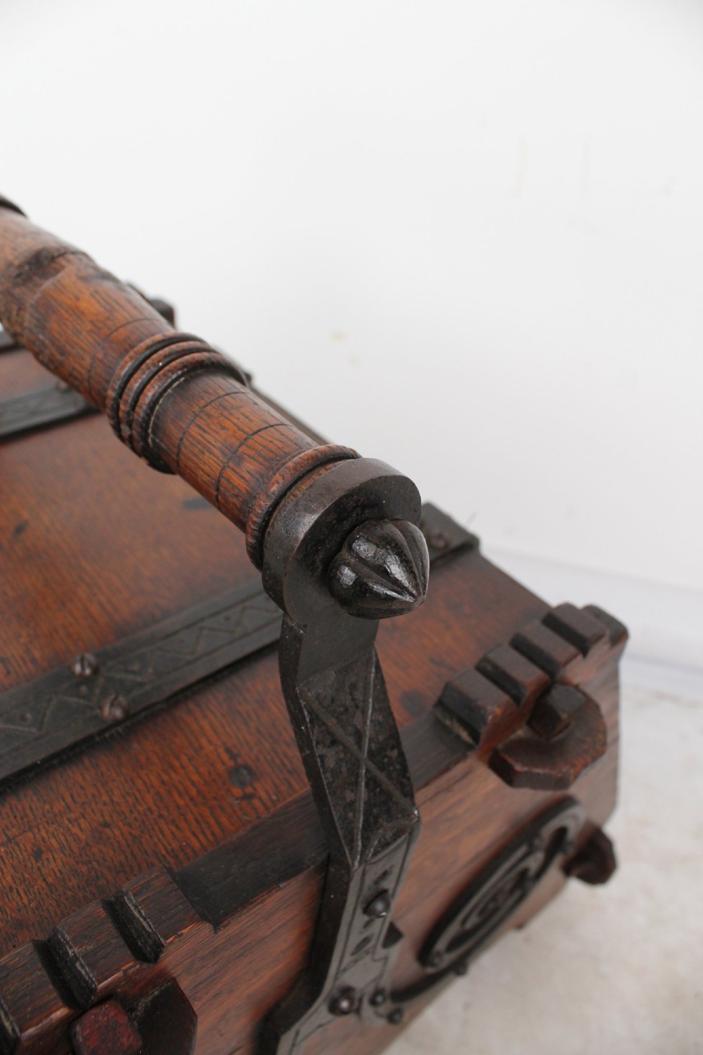 A Victorian Gothic Revival dark oak coal scuttle featuring sloped timber lids, a turned handle, and black wrought iron scrollwork straps. View XII