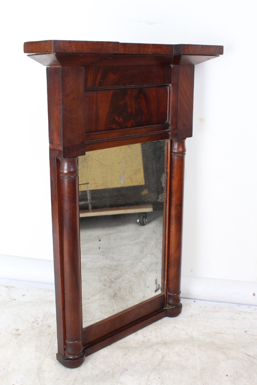 A small rectangular Regency mahogany pier mirror featuring an overhanging upper cornice, side column supports, and foxed glass. View II