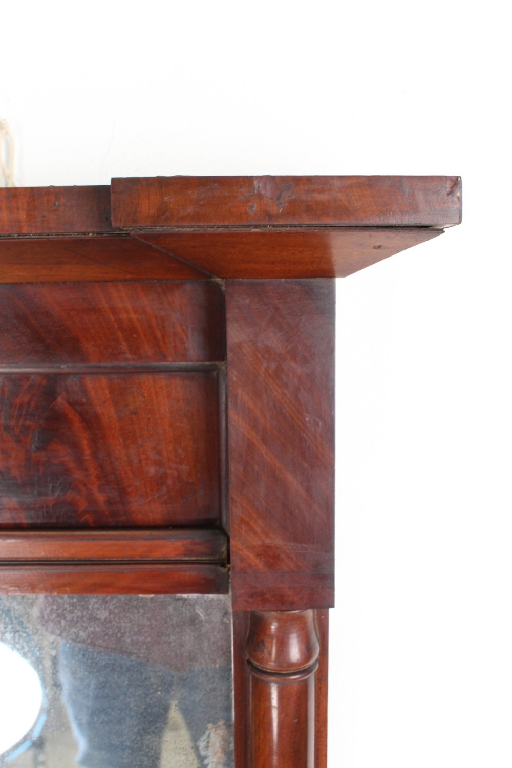 A small rectangular Regency mahogany pier mirror featuring an overhanging upper cornice, side column supports, and foxed glass. View V