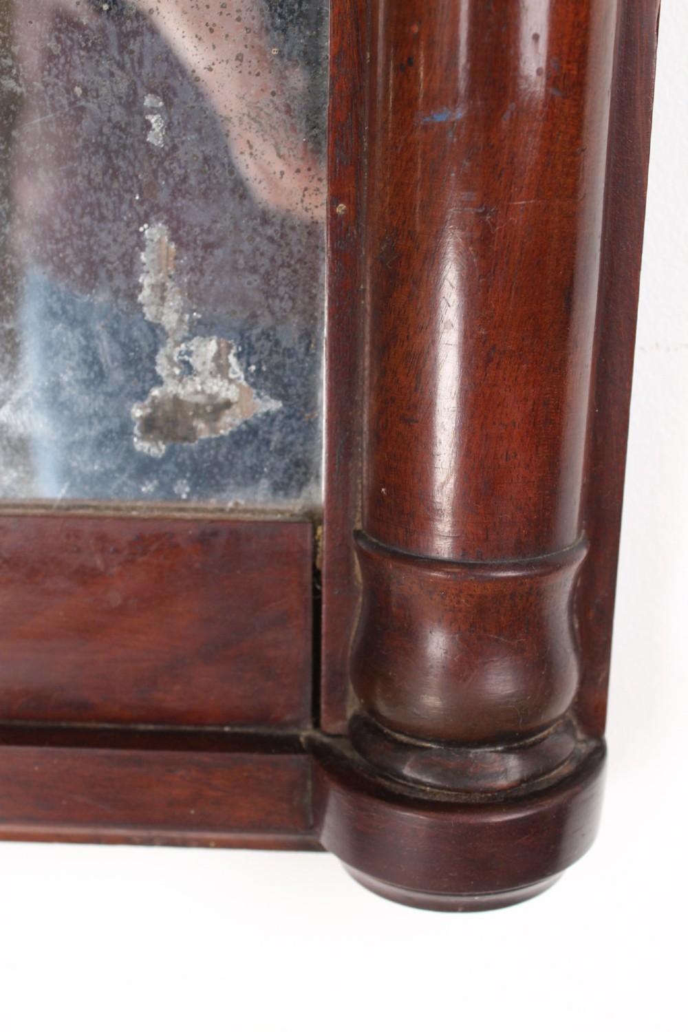 A small rectangular Regency mahogany pier mirror featuring an overhanging upper cornice, side column supports, and foxed glass. View IX