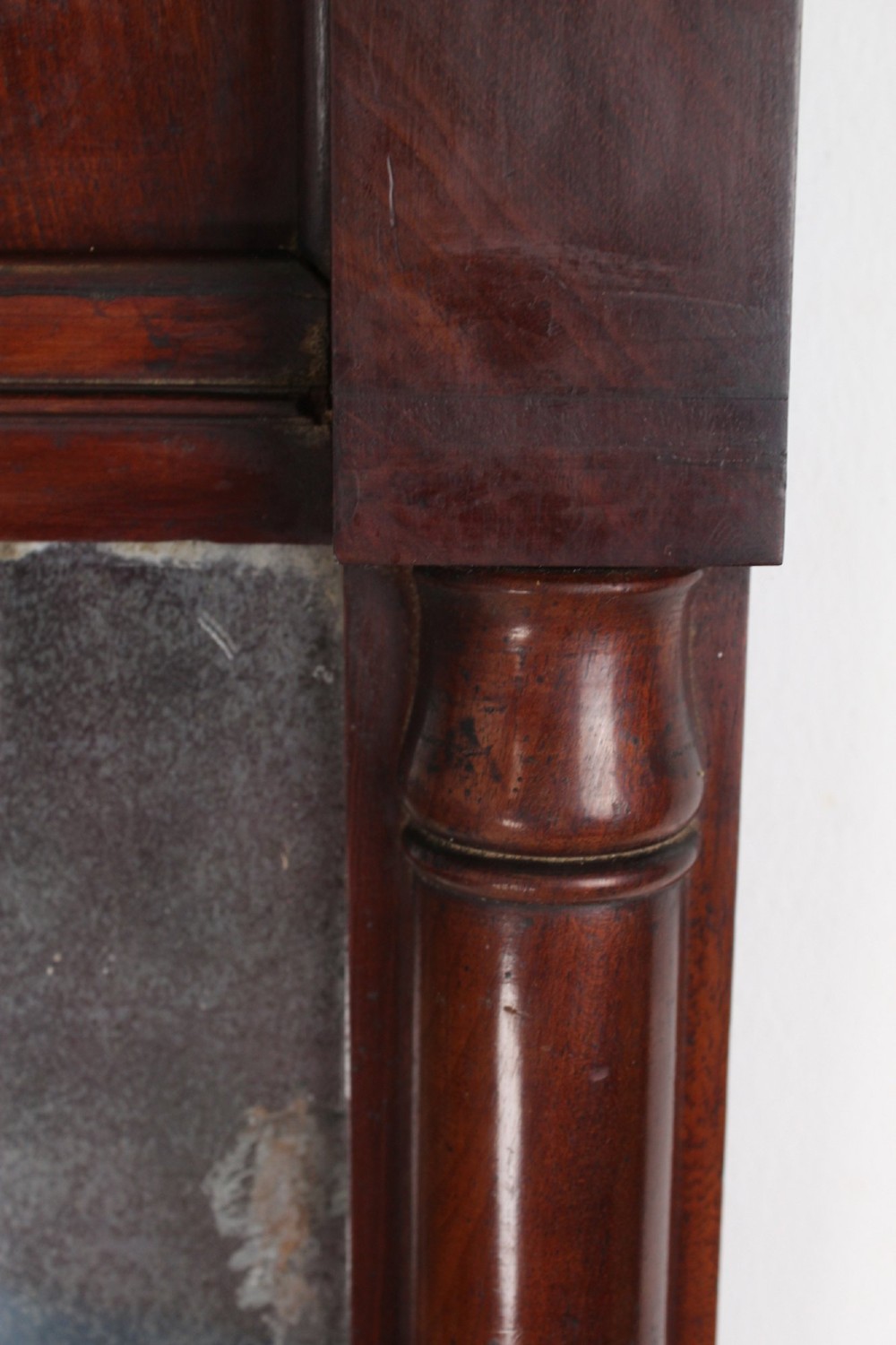 A small rectangular Regency mahogany pier mirror featuring an overhanging upper cornice, side column supports, and foxed glass. View X