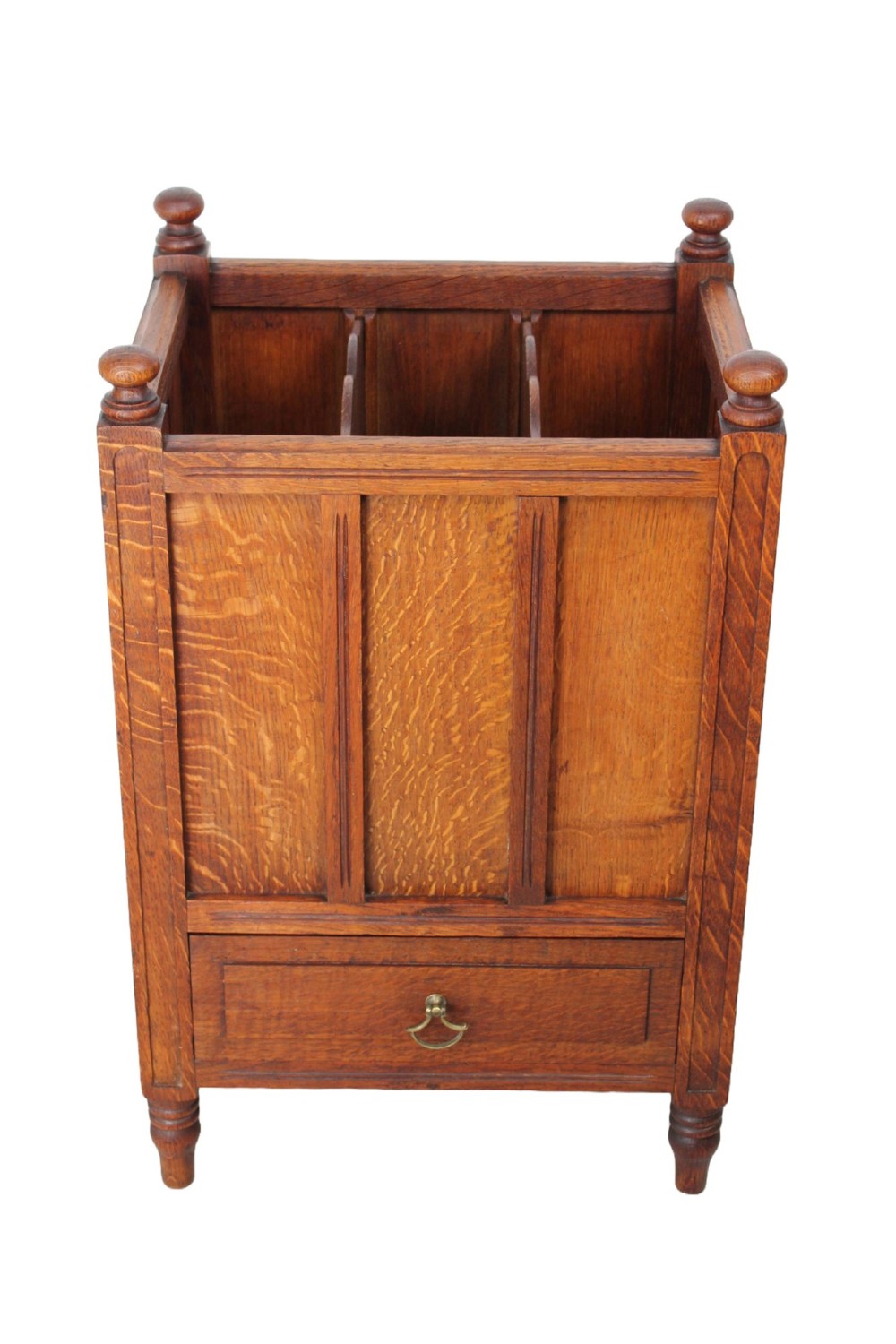 An Edwardian oak Canterbury with vertical panelled sides, internal dividers, a lower drawer with a brass handle, and corner finials. View II