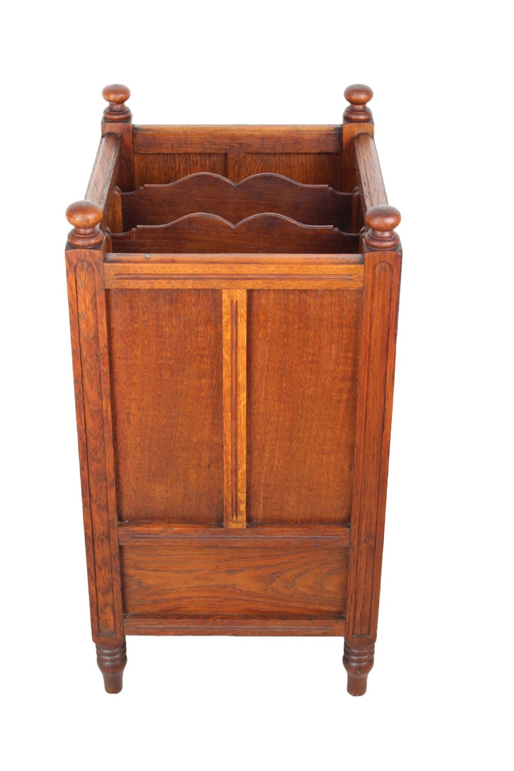 An Edwardian oak Canterbury with vertical panelled sides, internal dividers, a lower drawer with a brass handle, and corner finials. View III