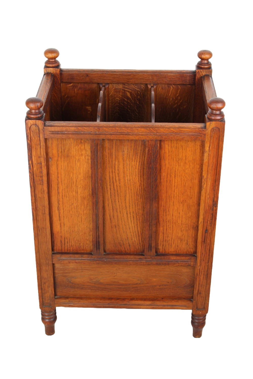 An Edwardian oak Canterbury with vertical panelled sides, internal dividers, a lower drawer with a brass handle, and corner finials. View IV
