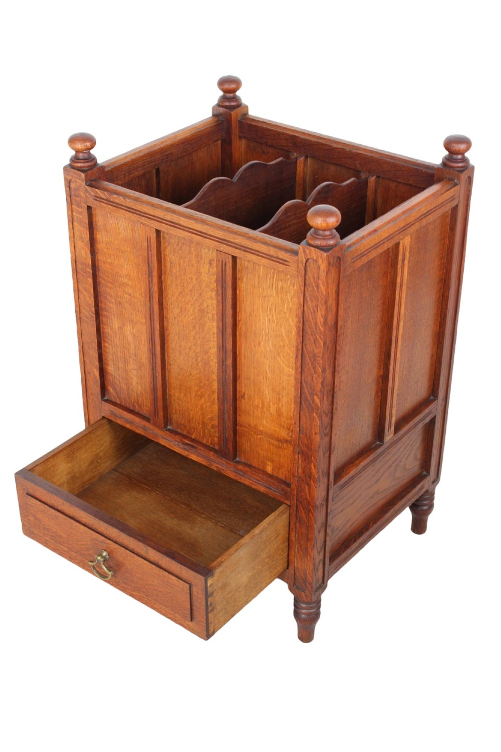 An Edwardian oak Canterbury with vertical panelled sides, internal dividers, a lower drawer with a brass handle, and corner finials. View V