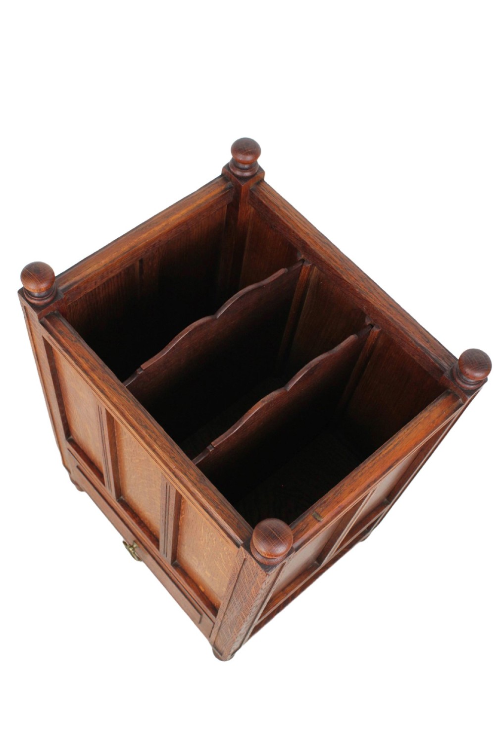 An Edwardian oak Canterbury with vertical panelled sides, internal dividers, a lower drawer with a brass handle, and corner finials. View VI