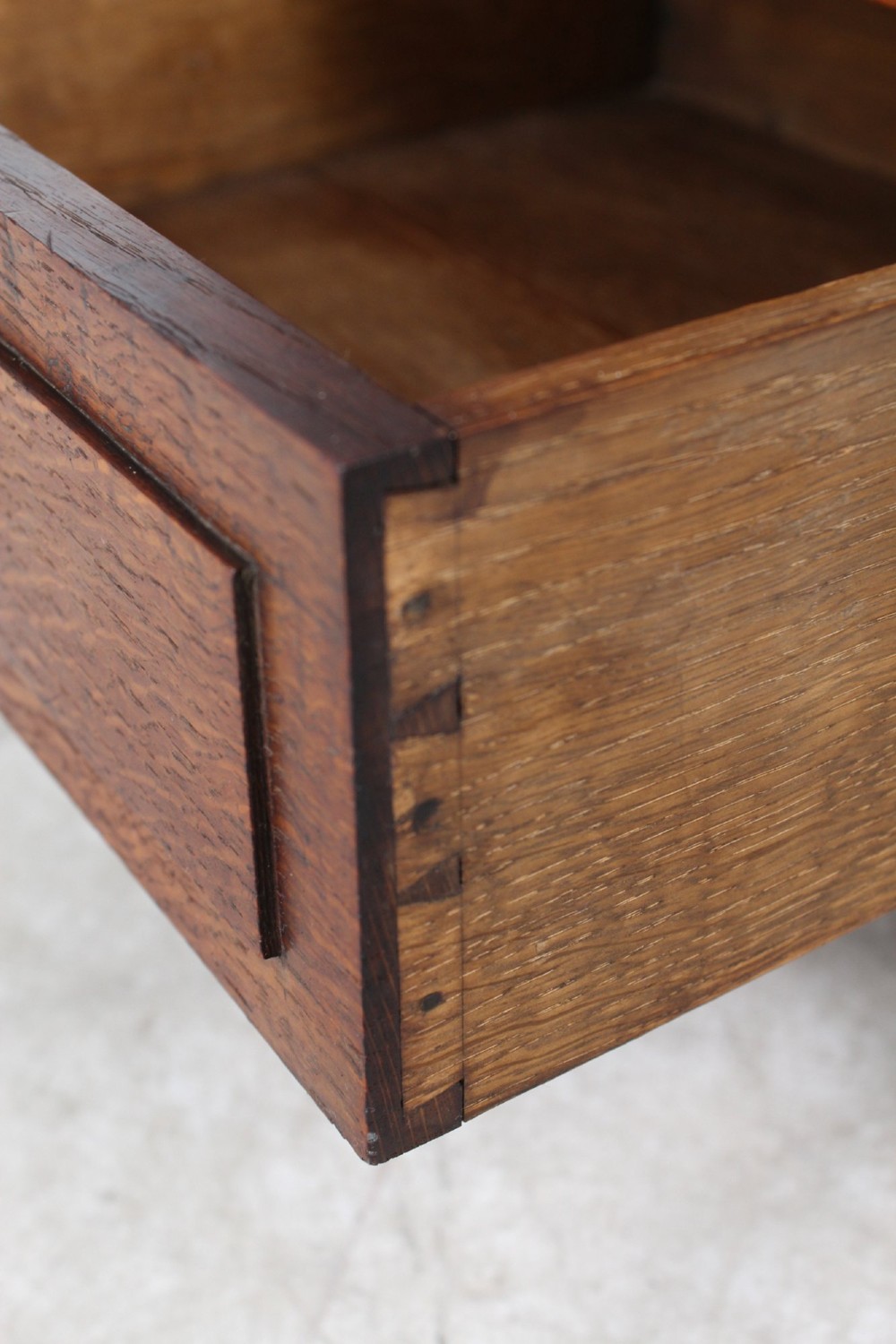An Edwardian oak Canterbury with vertical panelled sides, internal dividers, a lower drawer with a brass handle, and corner finials. View VII
