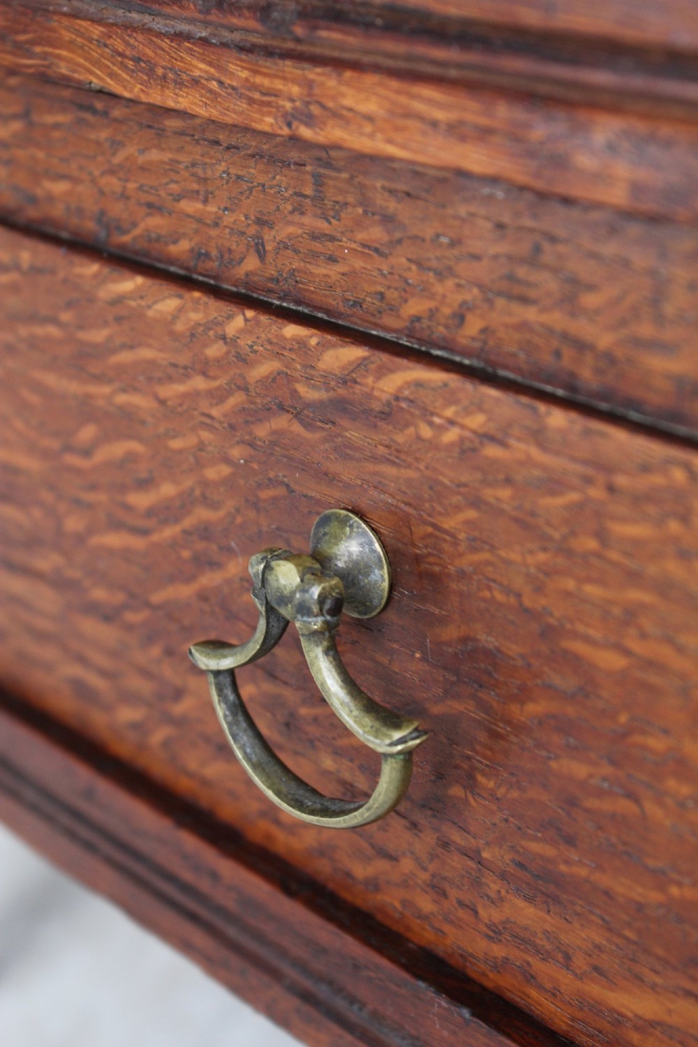 An Edwardian oak Canterbury with vertical panelled sides, internal dividers, a lower drawer with a brass handle, and corner finials. View X