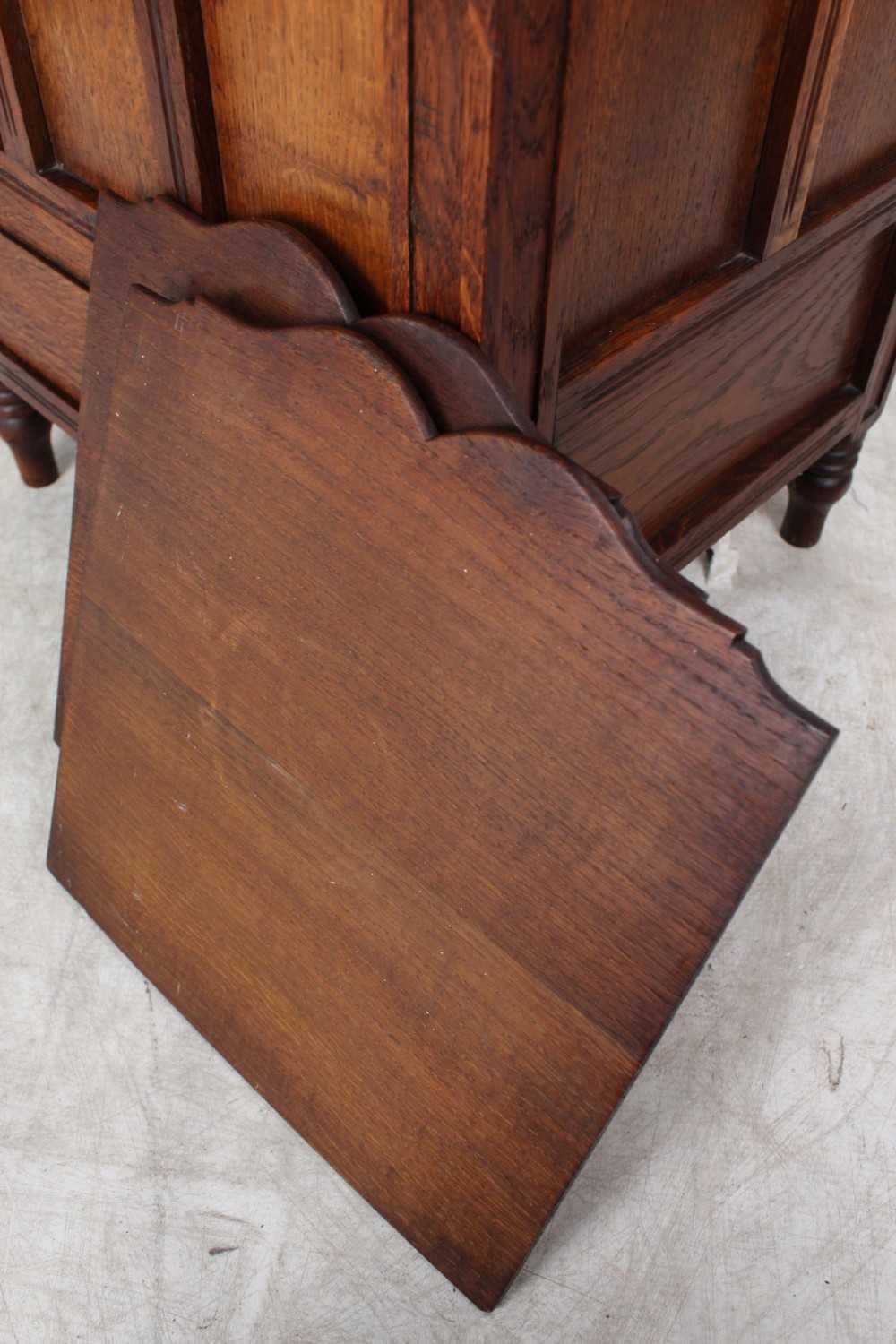 An Edwardian oak Canterbury with vertical panelled sides, internal dividers, a lower drawer with a brass handle, and corner finials. View XI