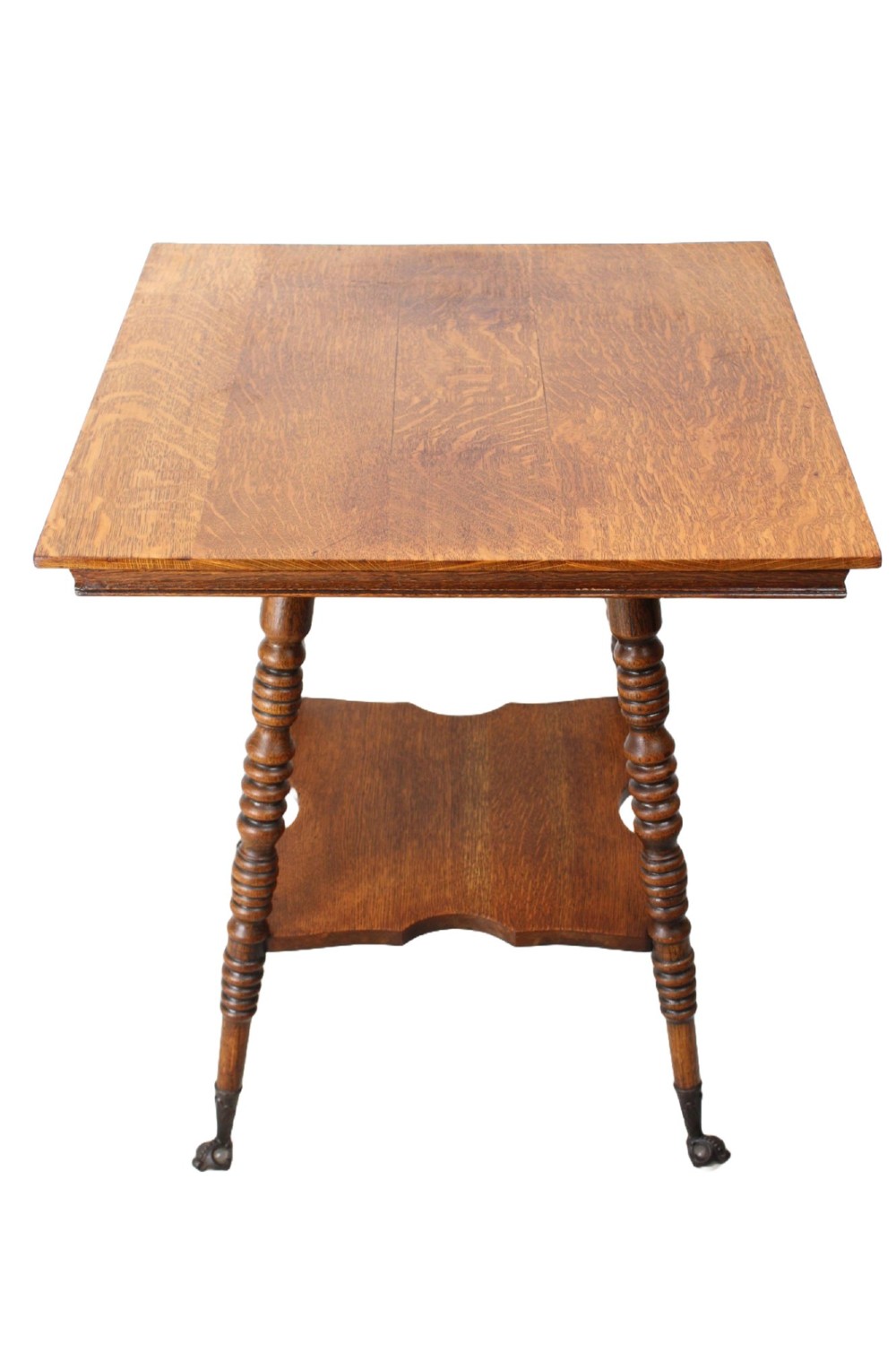 An antique warm brown oak side table featuring bobbin-turned legs, a lower rectangular shelf, and claw feet.
