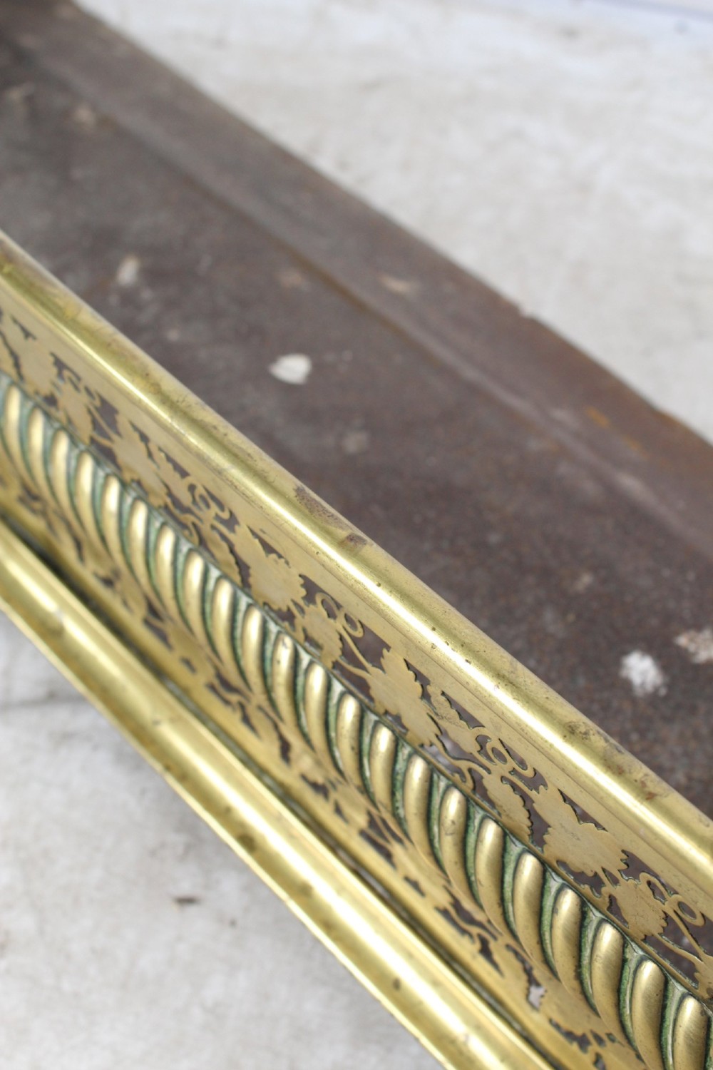 A low curved Victorian brass fire fender displaying a pierced fretwork panel, a central gadrooned band, and short cast scroll feet. View XI