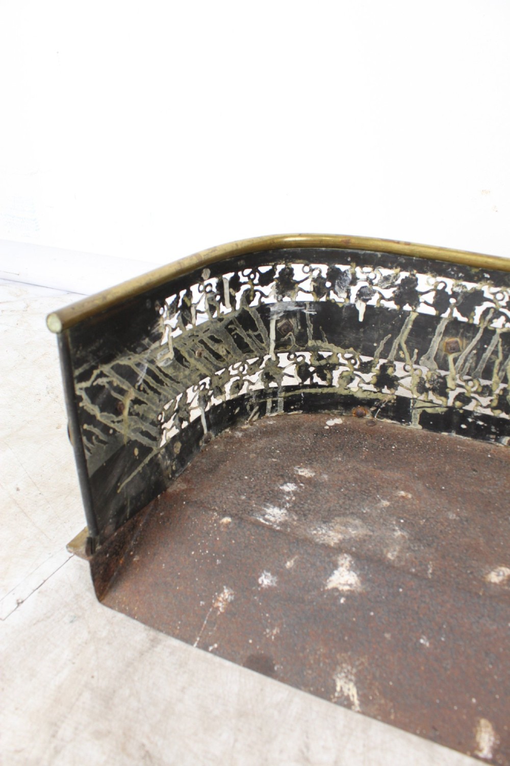 A low curved Victorian brass fire fender displaying a pierced fretwork panel, a central gadrooned band, and short cast scroll feet. View XII