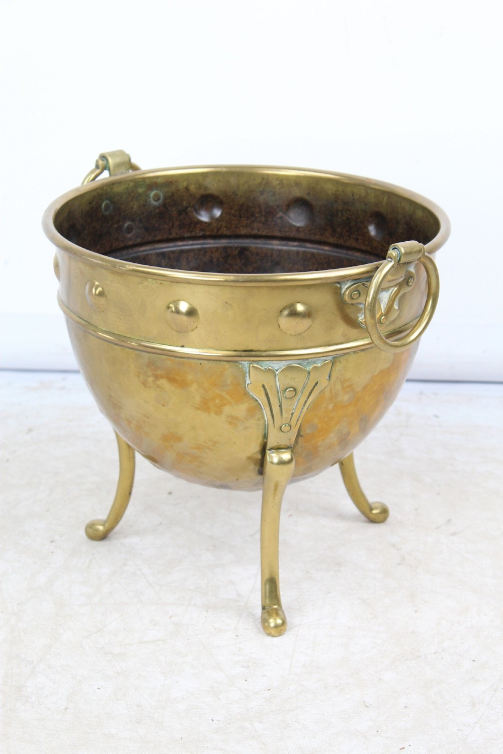 A Victorian Arts and Crafts brass log bin featuring raised round bosses around the rim, side drop rings, and curved legs. View II