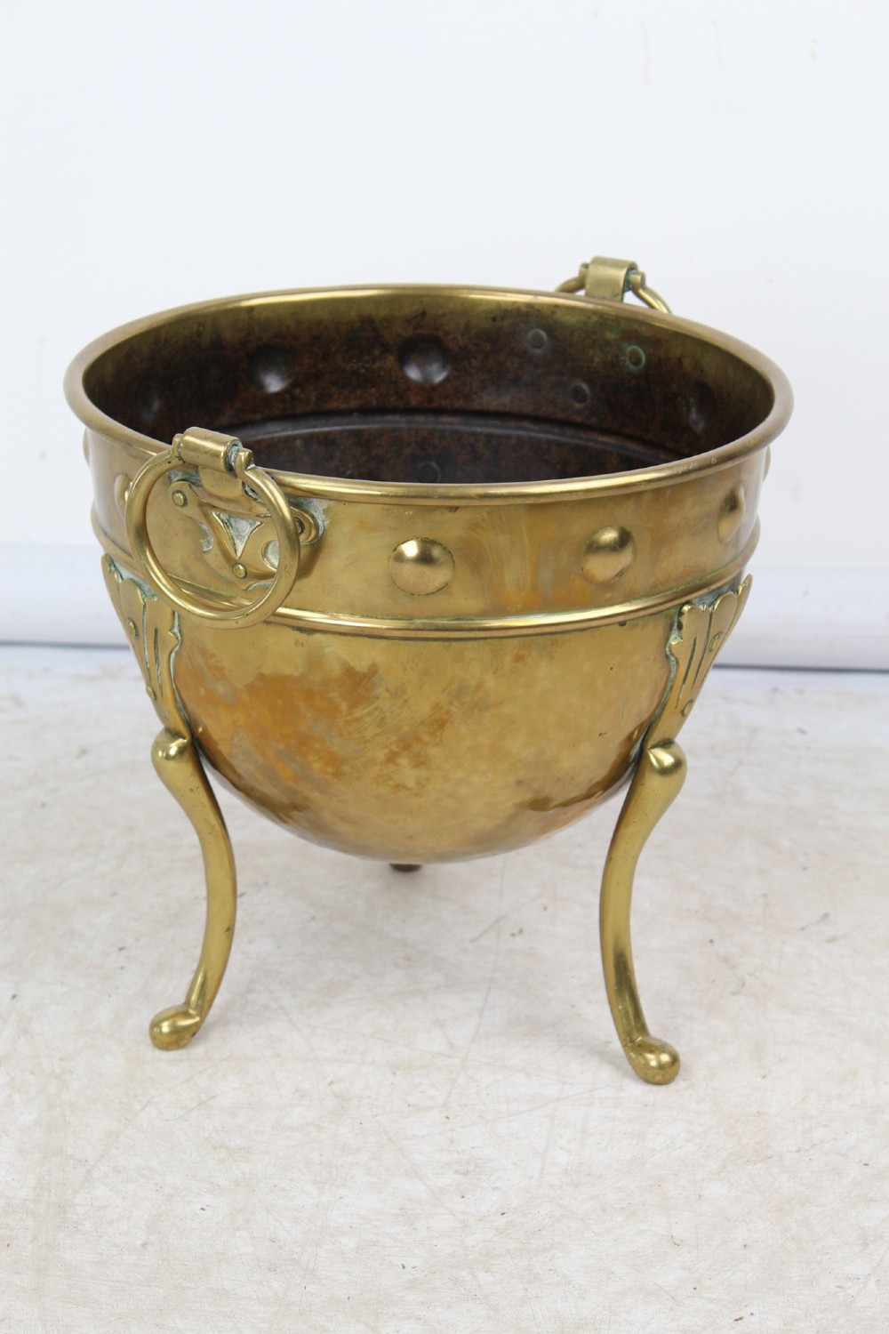 A Victorian Arts and Crafts brass log bin featuring raised round bosses around the rim, side drop rings, and curved legs. View III