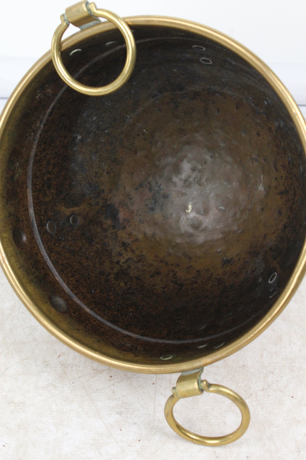 A Victorian Arts and Crafts brass log bin featuring raised round bosses around the rim, side drop rings, and curved legs. View VII