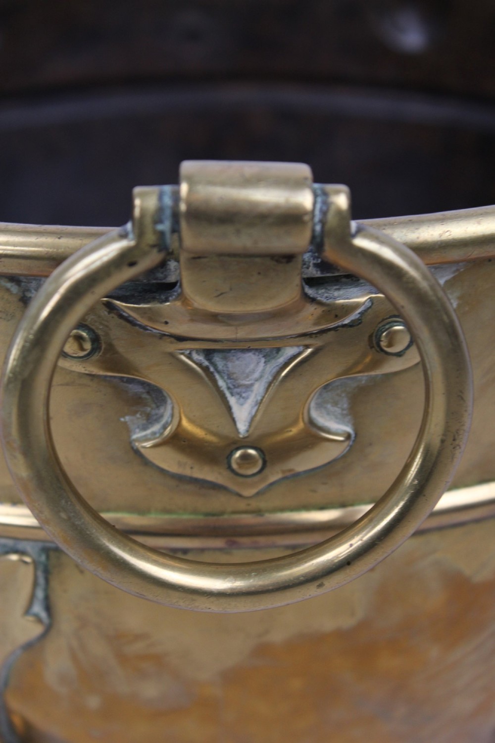 A Victorian Arts and Crafts brass log bin featuring raised round bosses around the rim, side drop rings, and curved legs. View XII