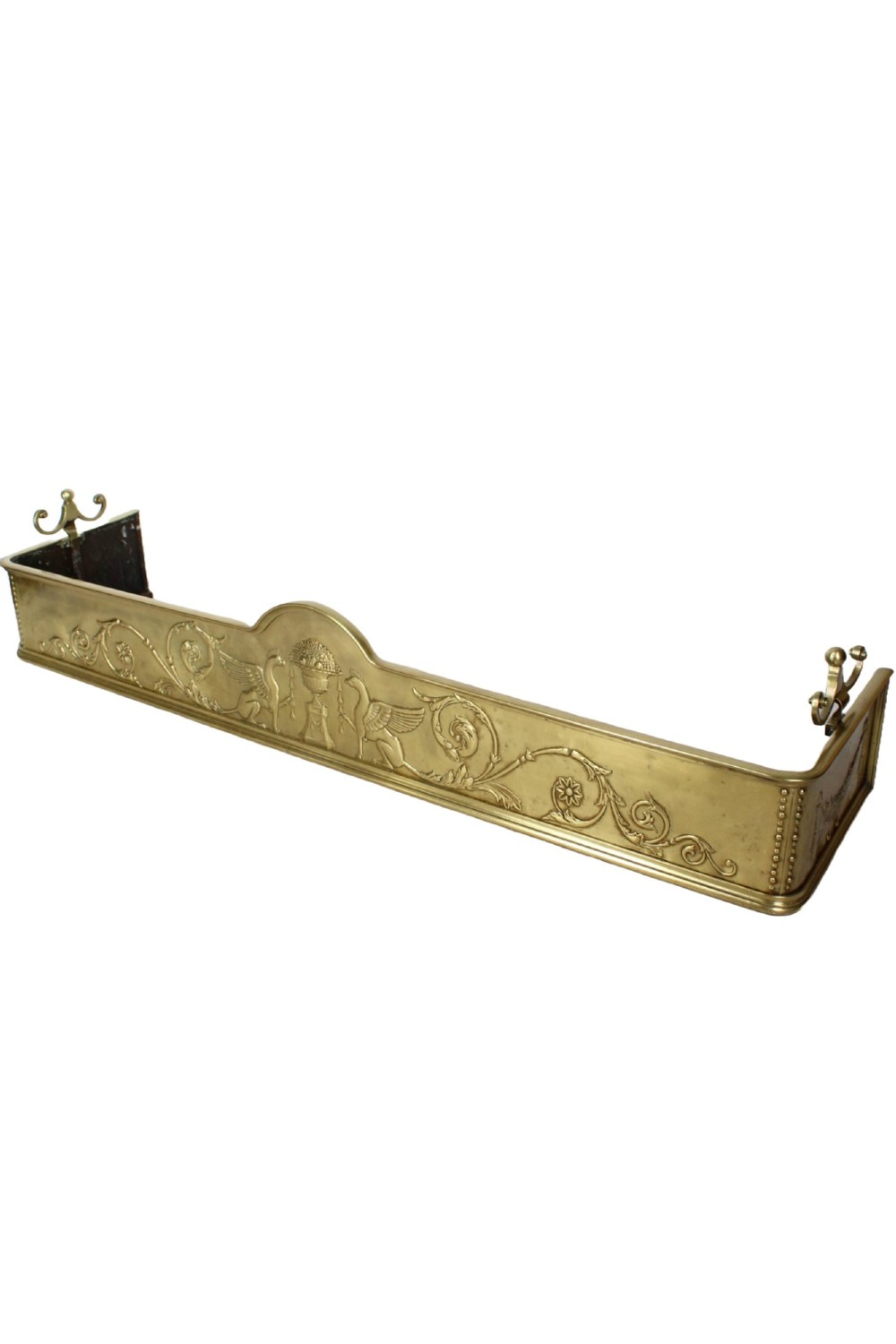 A long Victorian brass fireplace fender featuring embossed Neoclassical relief decoration of central urns, winged sphinxes, and foliate scrolls. View II