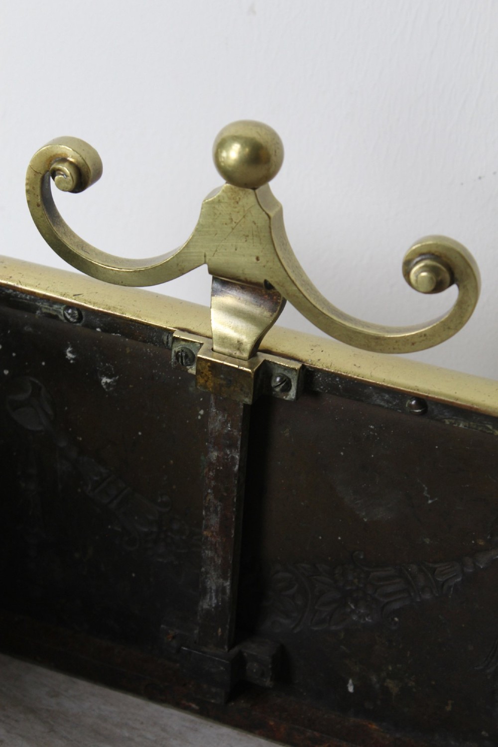 A long Victorian brass fireplace fender featuring embossed Neoclassical relief decoration of central urns, winged sphinxes, and foliate scrolls. View VIII
