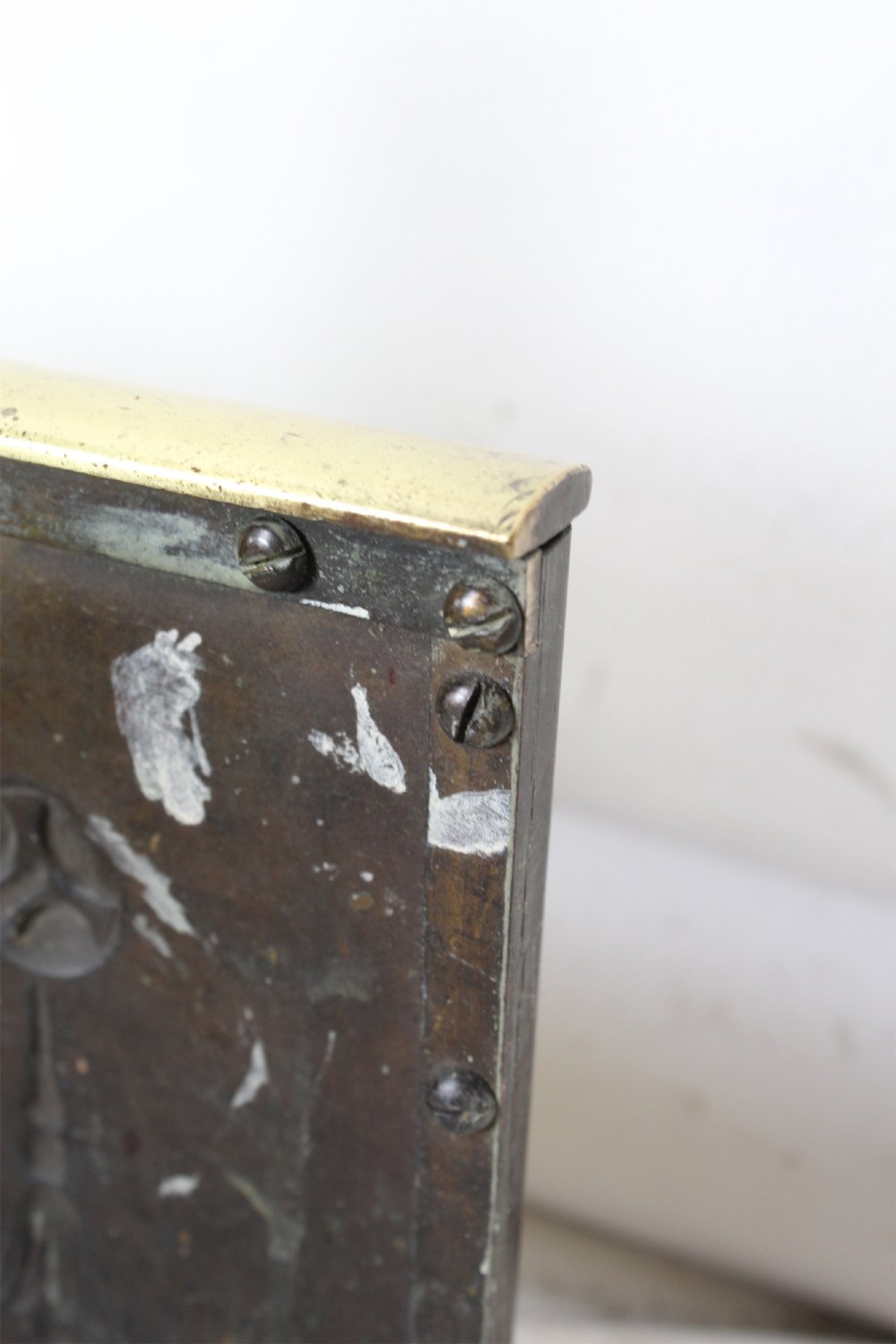 A long Victorian brass fireplace fender featuring embossed Neoclassical relief decoration of central urns, winged sphinxes, and foliate scrolls. View X