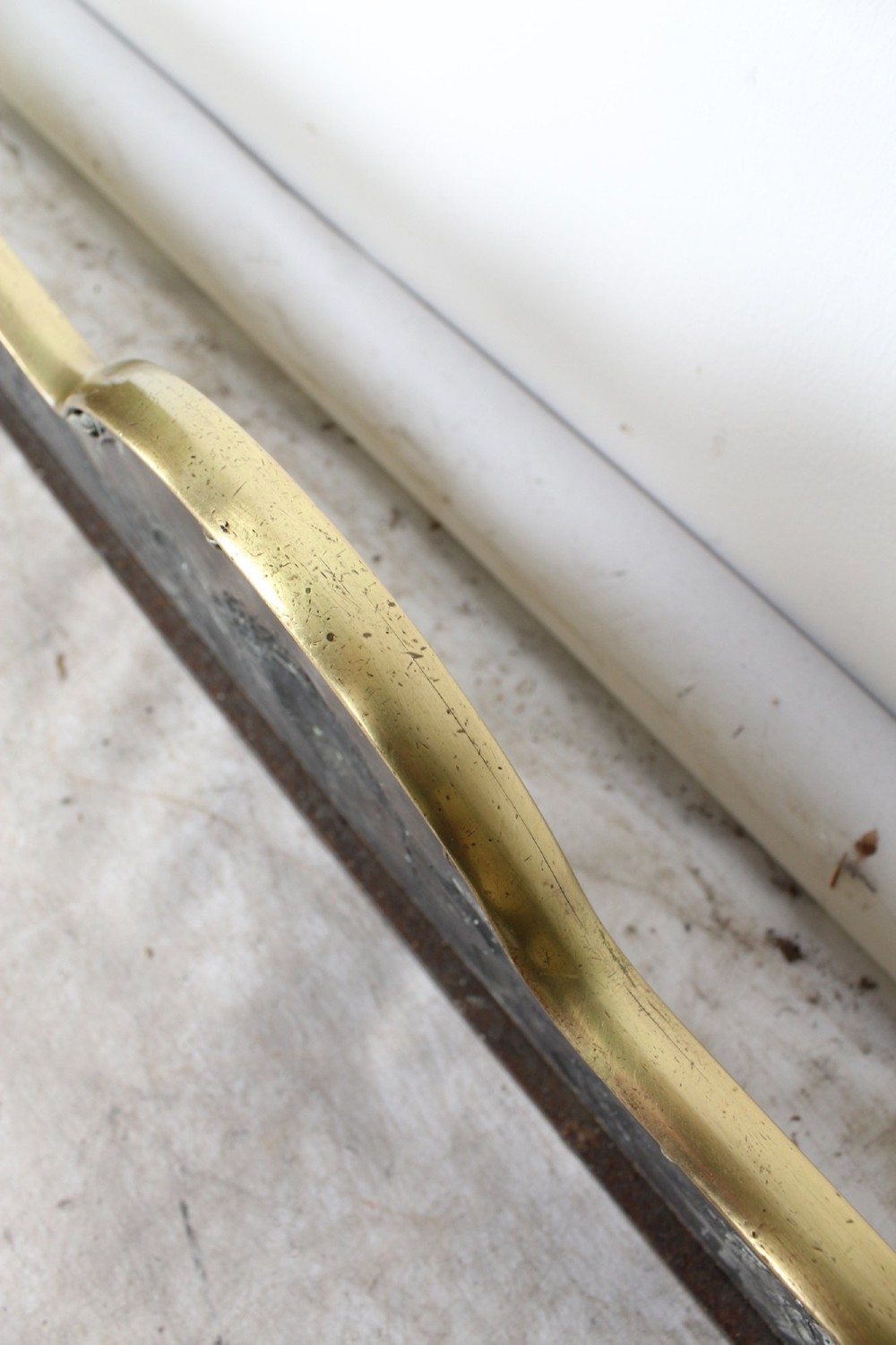 A long Victorian brass fireplace fender featuring embossed Neoclassical relief decoration of central urns, winged sphinxes, and foliate scrolls. View XI
