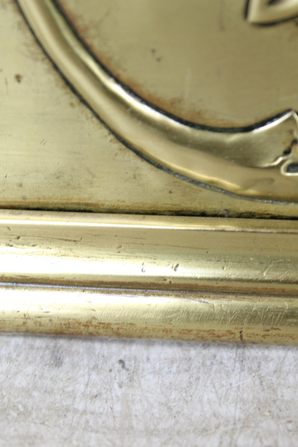 A long Victorian brass fireplace fender featuring embossed Neoclassical relief decoration of central urns, winged sphinxes, and foliate scrolls. View XIII