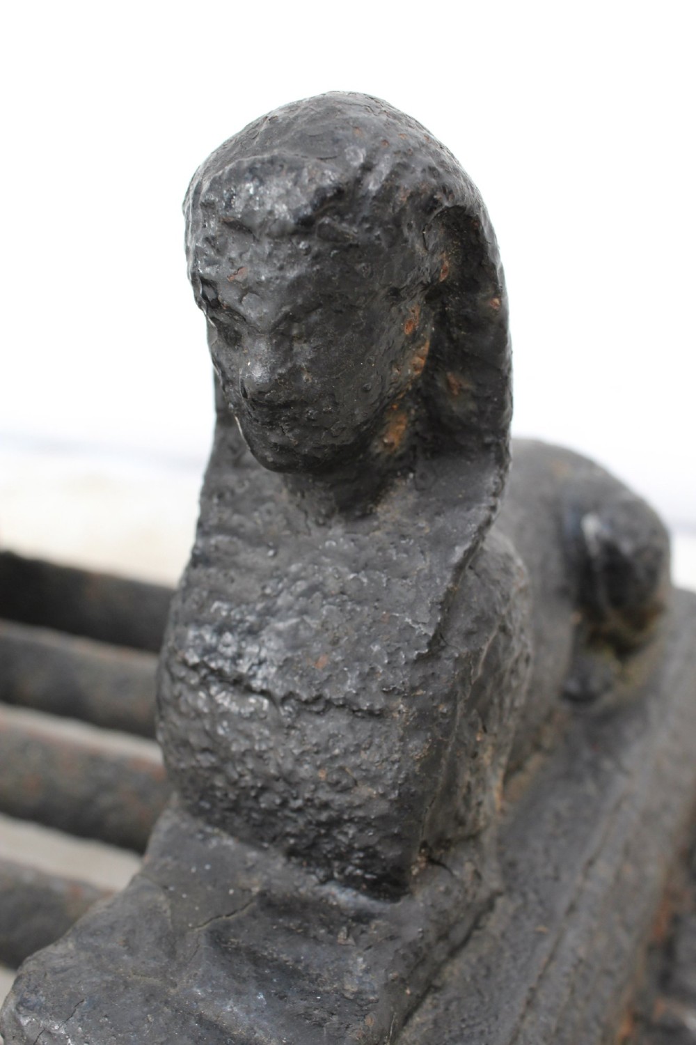 A dark cast iron boot scraper featuring twin sphinx figures flanking a central slatted grate set upon a decorative moulded base. View VIII