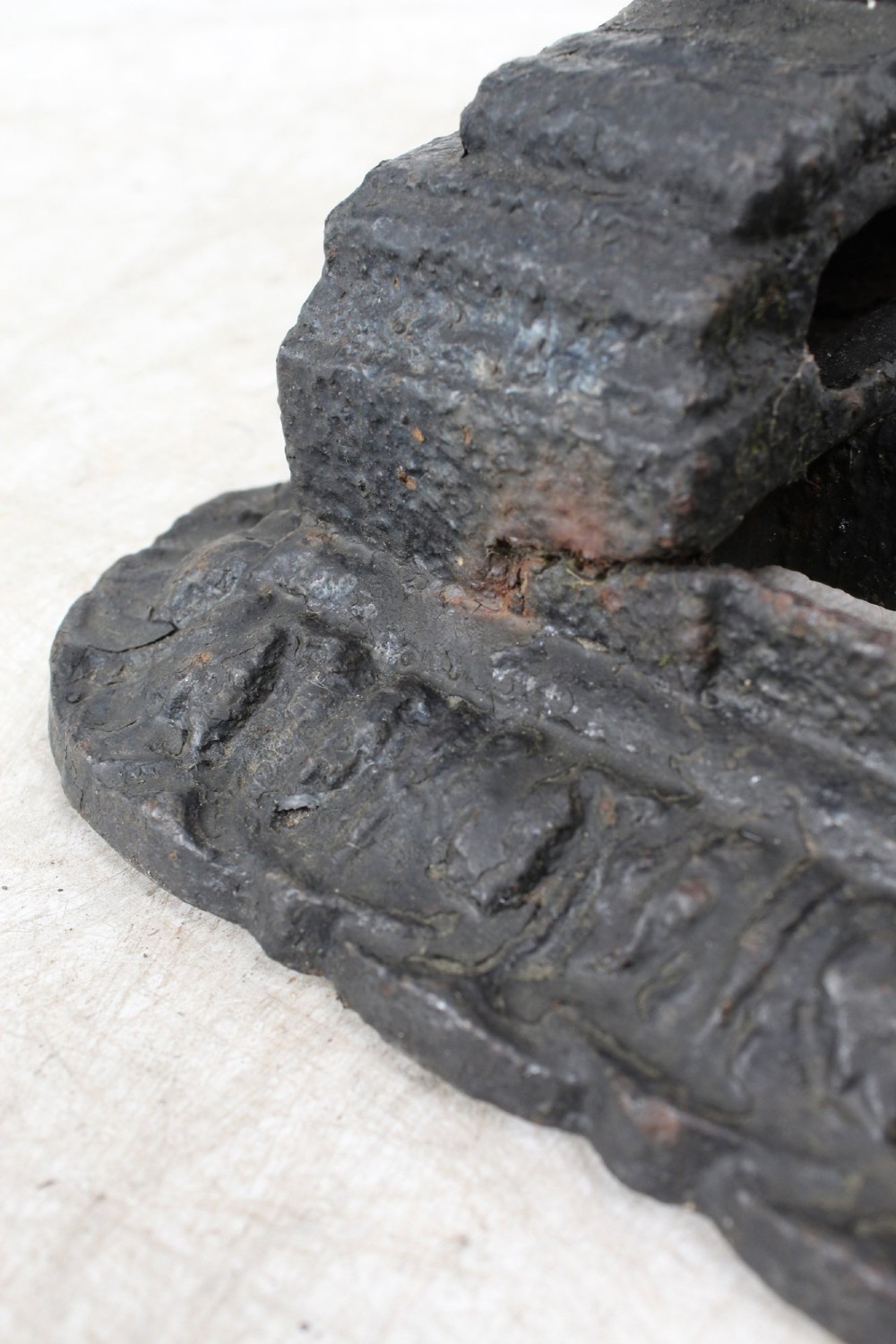 A dark cast iron boot scraper featuring twin sphinx figures flanking a central slatted grate set upon a decorative moulded base. View X