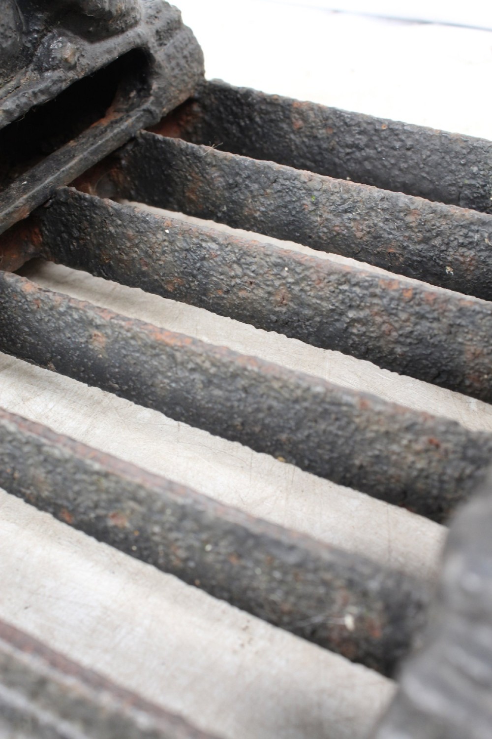 A dark cast iron boot scraper featuring twin sphinx figures flanking a central slatted grate set upon a decorative moulded base. View XI