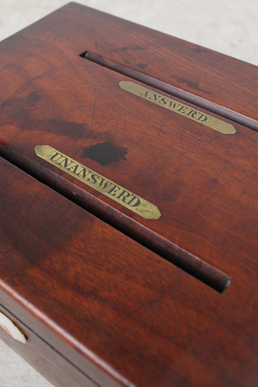 A Victorian mahogany letter box featuring two top slots labeled Answerd and Unanswerd with brass plaques and a circular keyhole escutcheon on the front. View XII