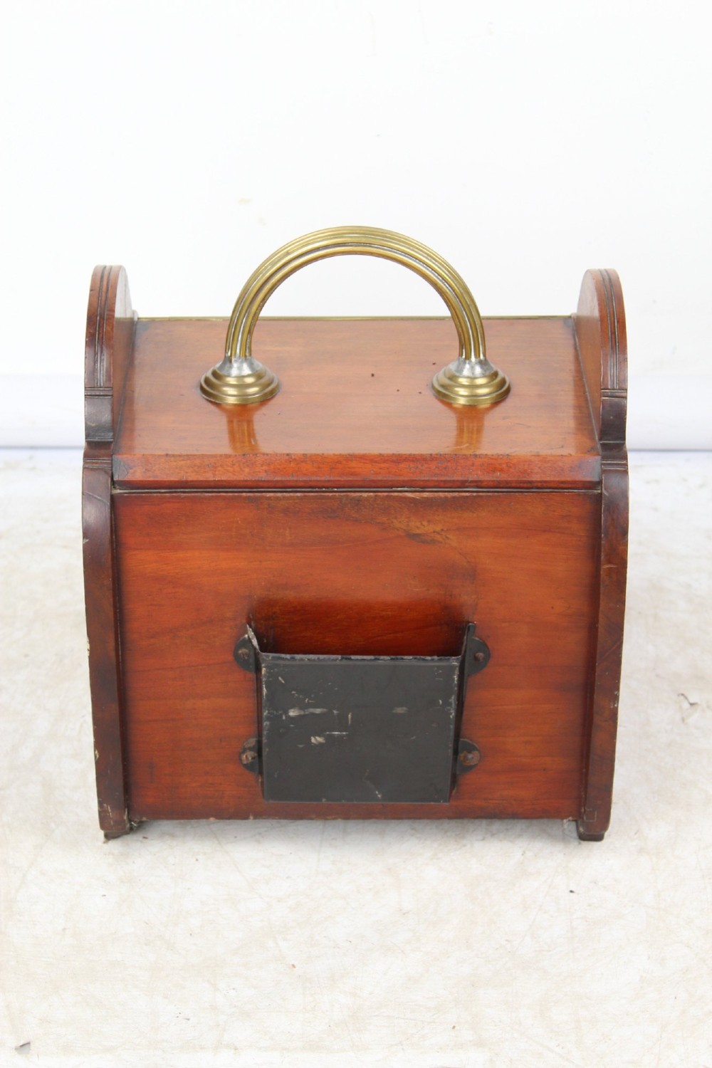A Victorian mahogany coal scuttle featuring a slanted drop-front door with decorative timber inlay and a polished brass carrying handle on top. View VI